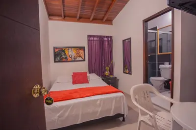 a bedroom with a bed with a red blanket at Hotel Palma De Sevilla Medellin in Medellín