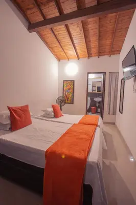 a bedroom with a bed with an orange blanket on it at Hotel Palma De Sevilla Medellin in Medellín