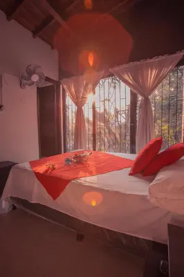 a bedroom with a bed with red pillows and a window at Hotel Palma De Sevilla Medellin in Medellín