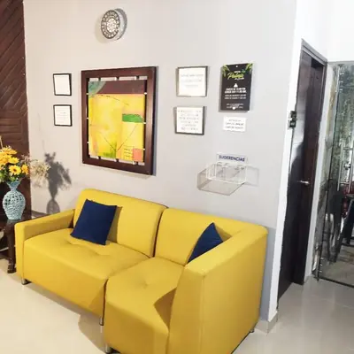 a yellow couch in a living room with a clock at Hotel Palma De Sevilla Medellin in Medellín