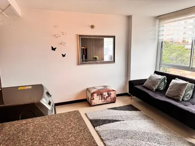 a living room with a black couch and a window at 2104 Apartamento Poblado en la zona rosa de medellín in Medellín