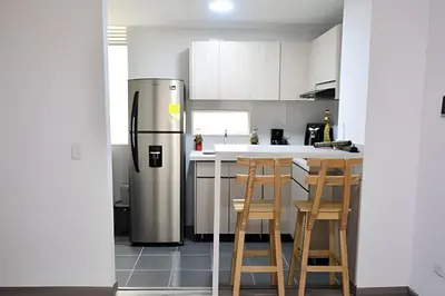a kitchen with a refrigerator and a table with chairs at Espectacular Apto Zona Rosa - Milán Estrato 5 in Manizales