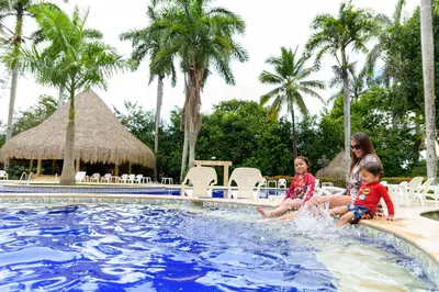 a woman and two children sitting in the pool at a resort at Finca Hotel Guadalupe in Santa Fe de Antioquia