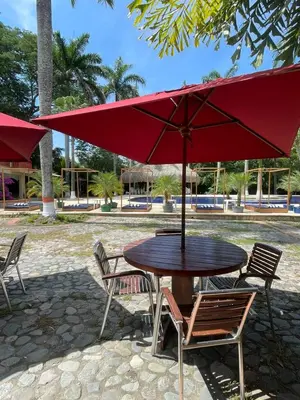 a table and chairs with a red umbrella at Finca Hotel Guadalupe in Santa Fe de Antioquia