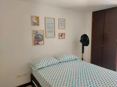 a bedroom with a bed and some pictures on the wall at Apartamento Laureles la 33 in Medellín