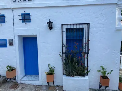 a white building with a blue door and some plants at Las 4 Estaciones Alojamientos de Ensueño Santorini Doradal in Puerto Triunfo