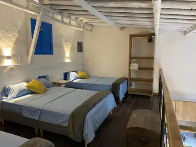two beds in a room with blue and yellow pillows at Las 4 Estaciones Alojamientos de Ensueño Santorini Doradal in Puerto Triunfo