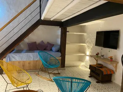 a bedroom with two chairs and a bed with a tv at Las 4 Estaciones Alojamientos de Ensueño Santorini Doradal in Puerto Triunfo
