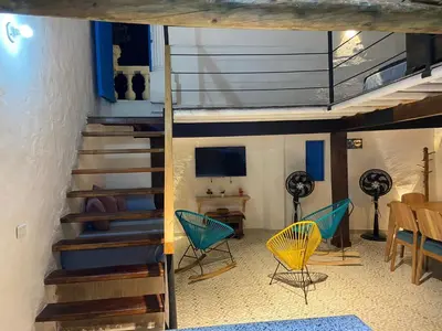 a room with stairs and chairs and a table at Las 4 Estaciones Alojamientos de Ensueño Santorini Doradal in Puerto Triunfo