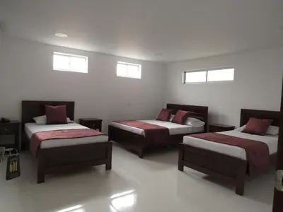 a room with three beds and two windows at Hotel Plaza Berlín in Medellín