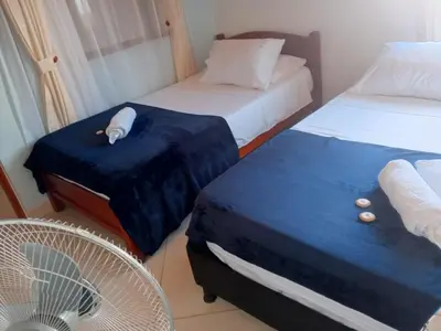 a room with two beds and a fan at Hotel El Balcon de madera in Norcasia