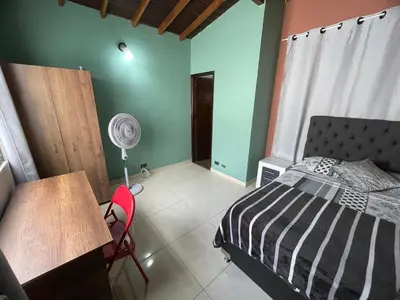 a bedroom with a bed and a desk and a fan at Apartamento Relax in Medellín