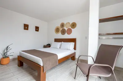 a white bedroom with a bed and a chair at Hotel Prada in Bello