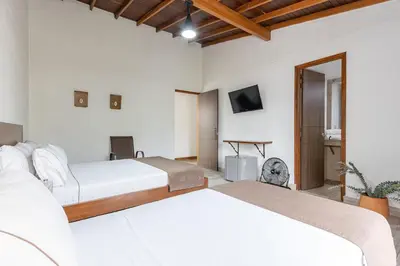 two beds in a white room with a tv at Hotel Prada in Bello