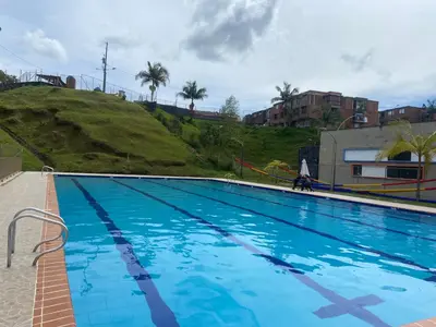 a large blue swimming pool with a hill in the background at Apartamento con Vista y acceso al lago en Guatape in Guatapé