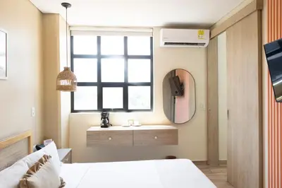 a bedroom with a bed and a window and a mirror at Mythical Hotel Boutique in Medellín