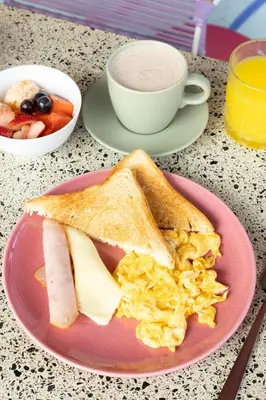 a pink plate with a breakfast sandwich and a cup of coffee at Mythical Hotel Boutique in Medellín