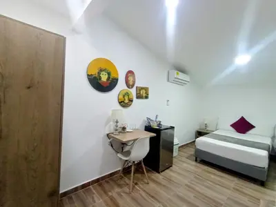 a bedroom with a bed and a desk and a table at Aguacatala Hotel Boutique in Medellín