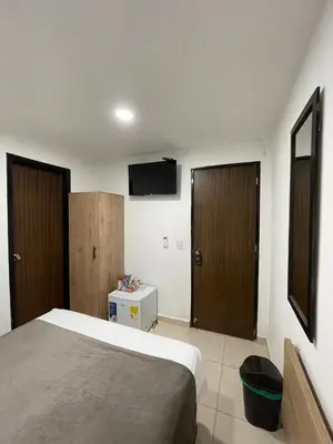 a bedroom with a bed and a flat screen tv at Aguacatala Hotel Boutique in Medellín