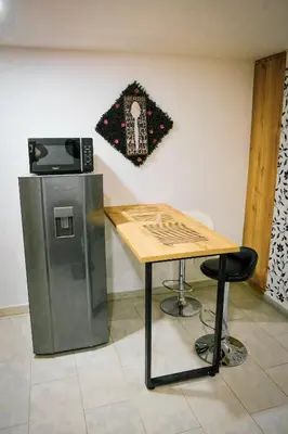 a table next to a refrigerator and a table with a chair at Acogedor loft frente al tranvía in Medellín