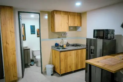 a kitchen with wooden cabinets and a stainless steel refrigerator at Acogedor loft frente al tranvía in Medellín