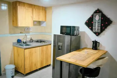 a small kitchen with a refrigerator and a table at Acogedor loft frente al tranvía in Medellín