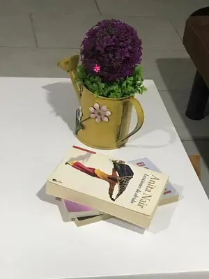 a book and a vase with purple flowers on a table at Acogedor loft frente al tranvía in Medellín