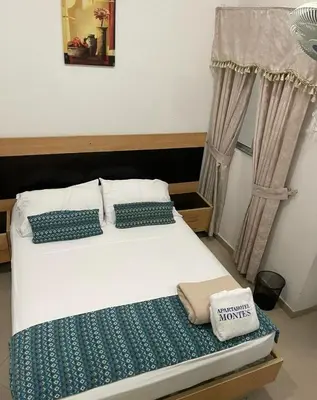 a white bed with blue pillows in a bedroom at LIVING Montes in Medellín