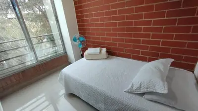 a bedroom with a brick wall and a bed with pillows at LIVING Montes in Medellín