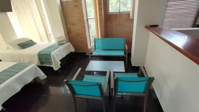a room with two beds and two chairs and a table at LIVING Montes in Medellín