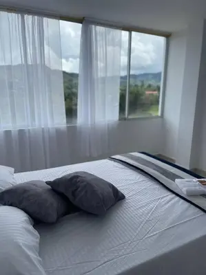 a bed with two pillows in front of a window at Linda casa con espectacular vista embalse y piedra in Guatapé