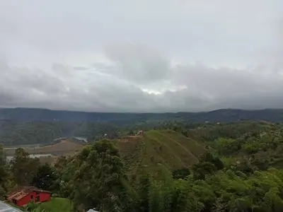 a green hill with a house on top of it at Linda casa con espectacular vista embalse y piedra in Guatapé