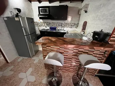 a kitchen with a refrigerator and a counter with stools at Aparta Suite Torre De Prado 503 in Medellín