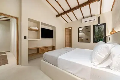 a white bedroom with a bed and a tv at Provenza 6 Bedroom House by HOUSY HOST in Medellín