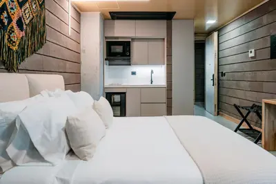a bedroom with a white bed and a kitchen at Hotel Living by Armoniko in Medellín