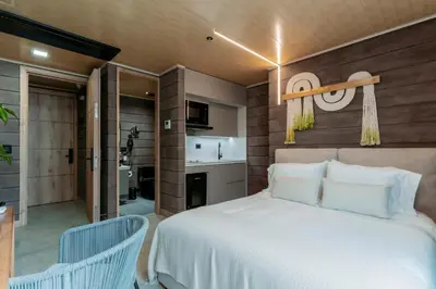 a bedroom with a white bed and a kitchen at Hotel Living by Armoniko in Medellín