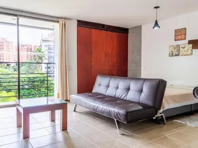 a living room with a leather couch and a bed at Flat Apartamento Great Location Poblado in Medellín