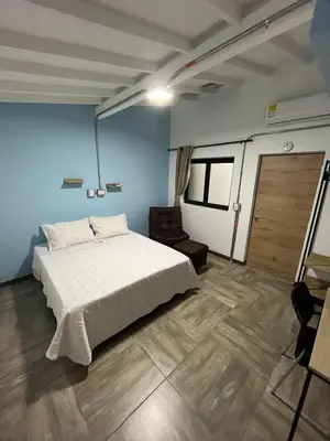 a bedroom with a white bed and a chair at CoLinkHouse Hotel in Medellín