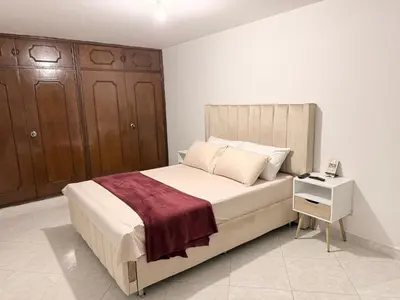 a bedroom with a large bed and a night stand at Alojamiento Laureles la 33 in Medellín