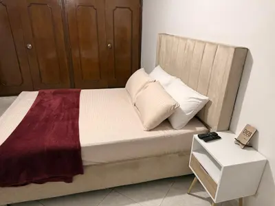 a bedroom with a bed with a wooden headboard and a table at Alojamiento Laureles la 33 in Medellín