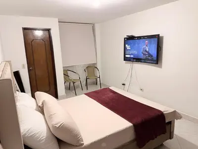a bedroom with a bed and a flat screen tv on the wall at Alojamiento Laureles la 33 in Medellín