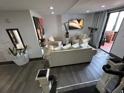 a living room with a white couch and wooden floors at El Balcón De Las Montañas in Medellín