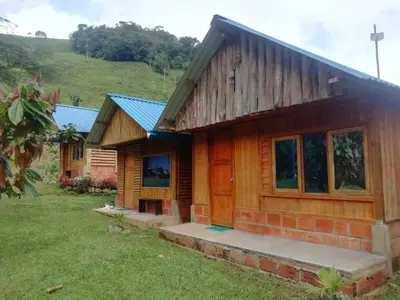 a log cabin with a green hill in the background at Cabañas orquídea in Norcasia