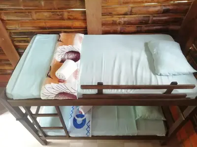 a bunk bed with white sheets and pillows on it at Cabañas orquídea in Norcasia