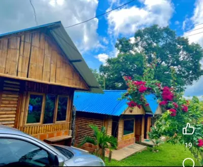 a wooden house with a blue roof and flowers at Cabañas orquídea in Norcasia