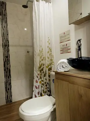 a bathroom with a toilet and a shower curtain at Laureles Guest House LGH Hotel in Medellín