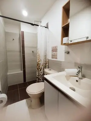 a white bathroom with a toilet and a sink at Laureles Guest House LGH Hotel in Medellín