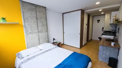 a bedroom with a large bed and a yellow wall at Ulivin Coliving in Manizales