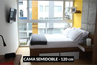 a bedroom with a bed and a large window at Ulivin Coliving in Manizales