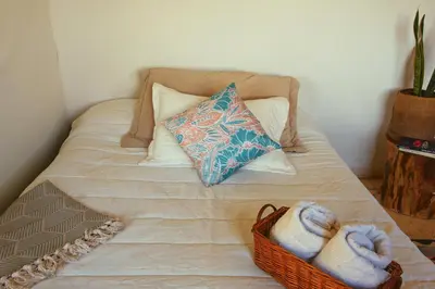 a bed with a basket of towels and a pillow at Casa Mostaza-Ecolodge in Samaná